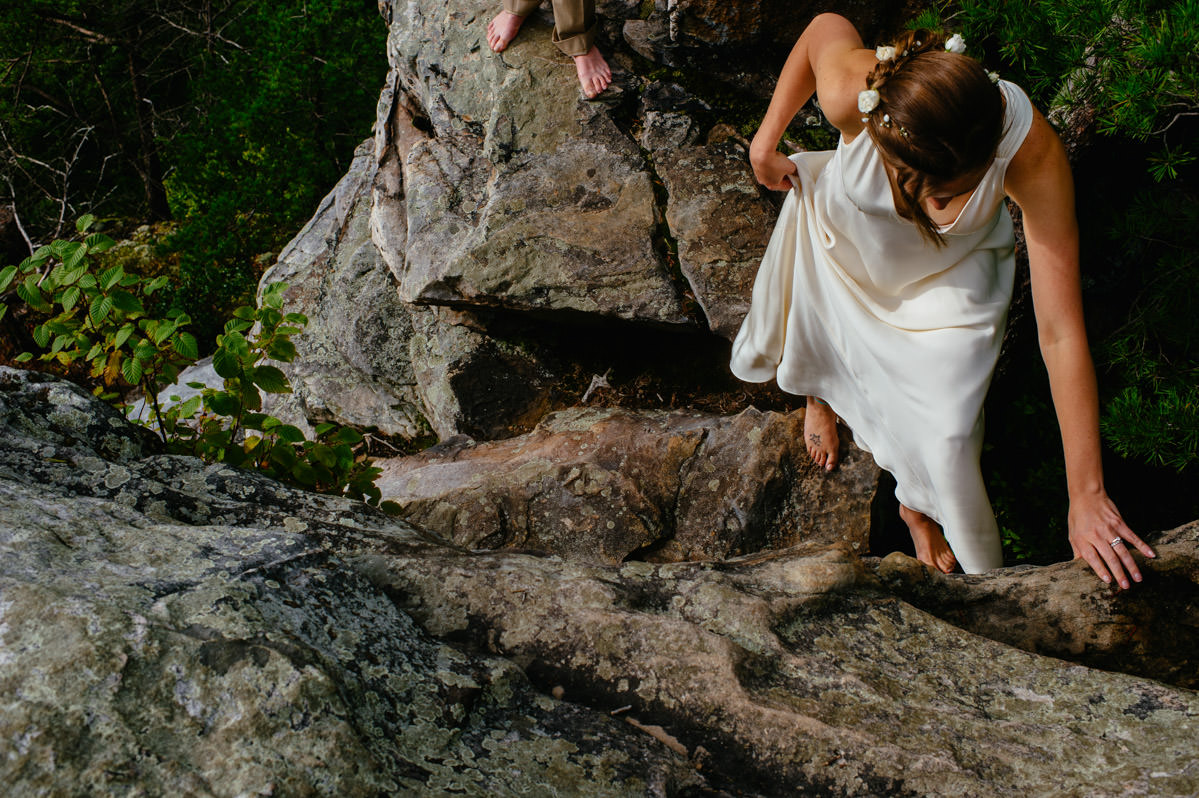 fayetteville bride climbing rocks on wedding day by theoberports
