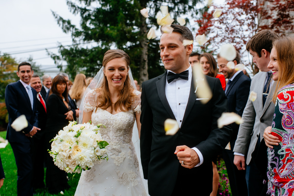 guests throwing flower petals at bride and groom as they leave the church