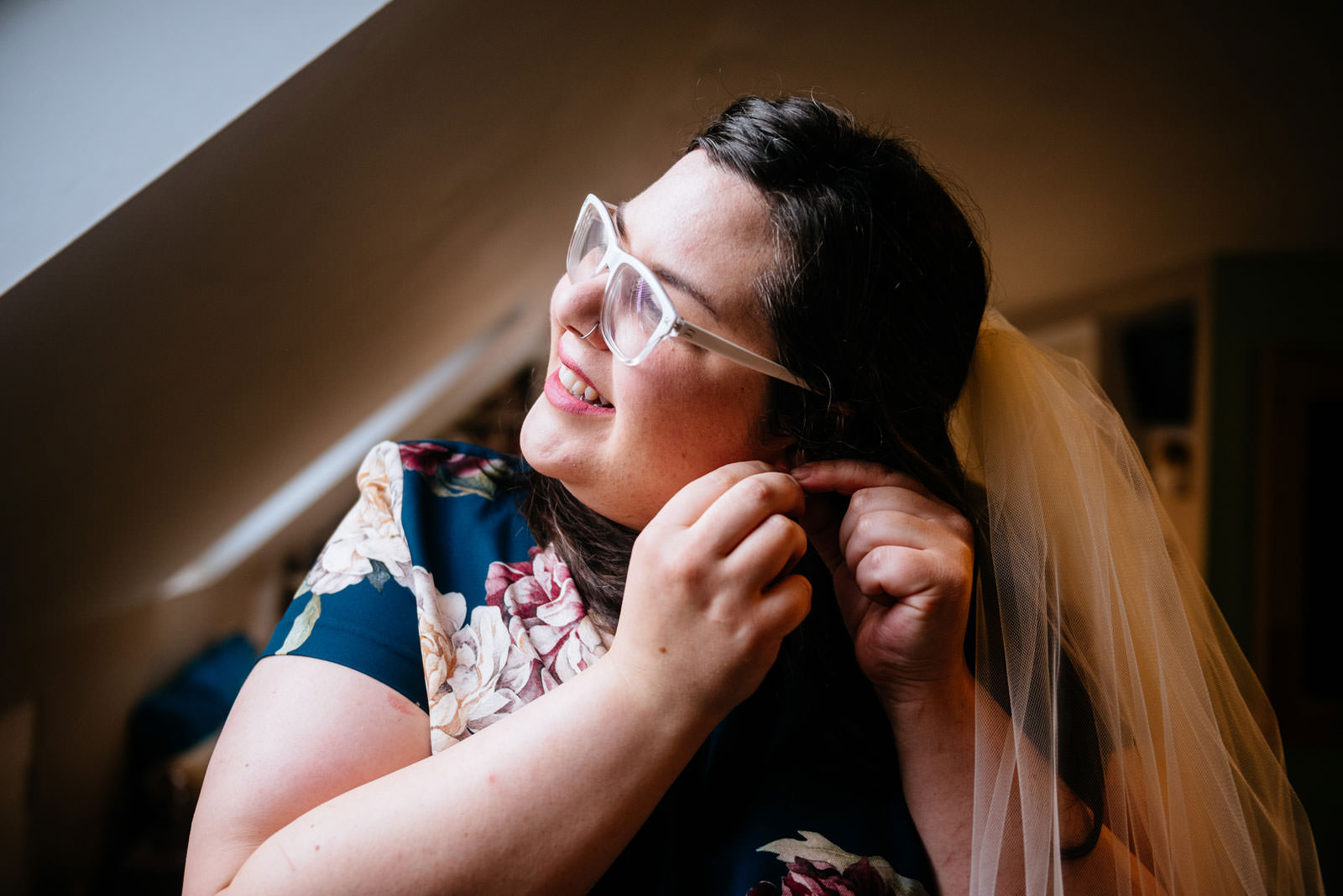 bride putting on earrings in apartment