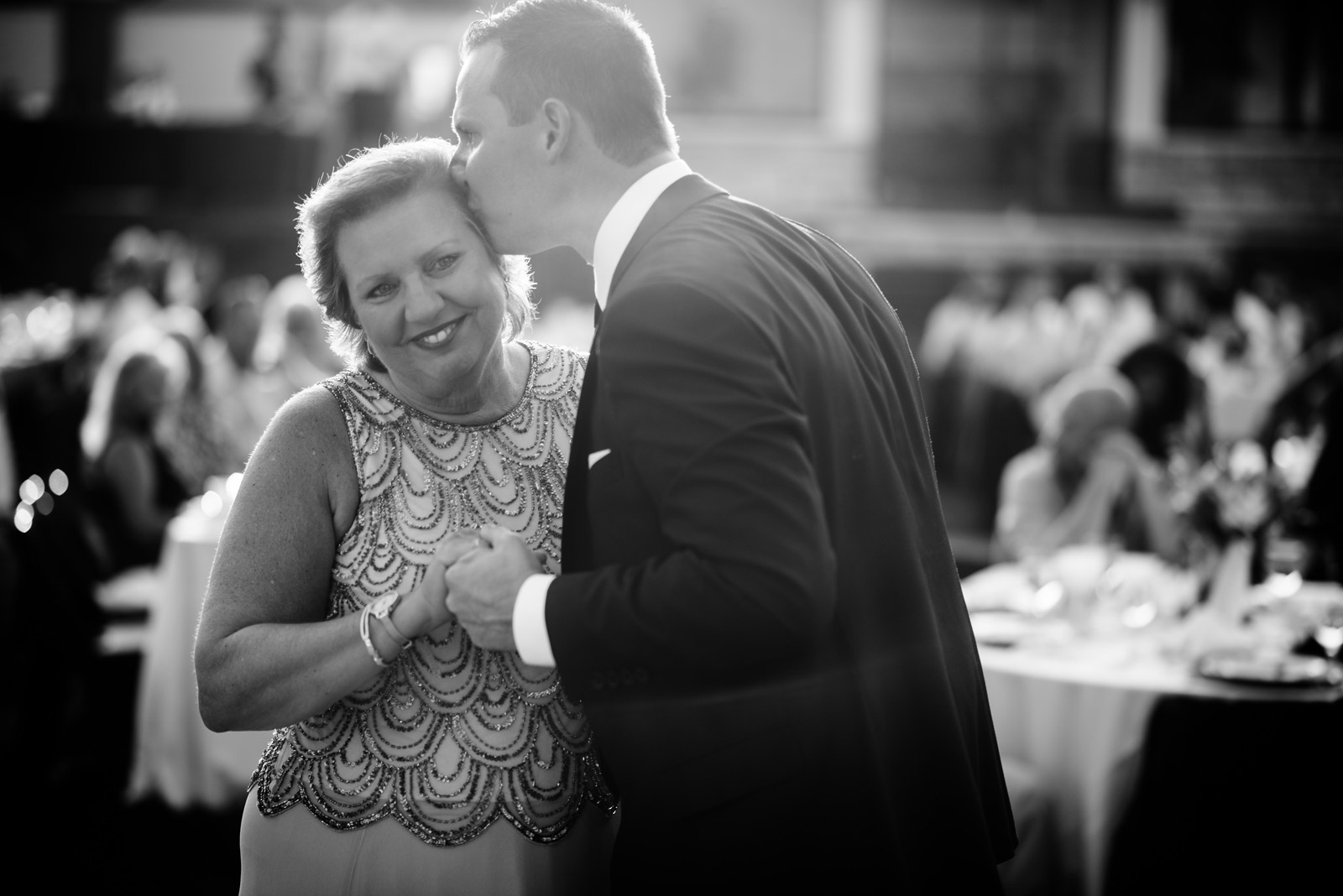 groom kissing mom during mother son dance