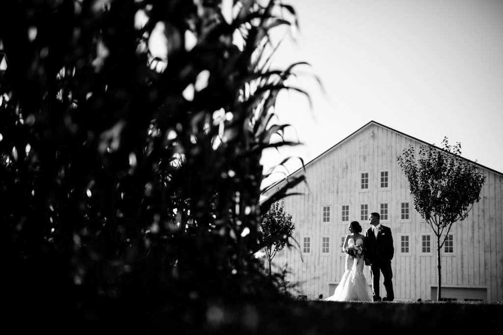 bride and groom in front of white barn at lucas farm wedding
