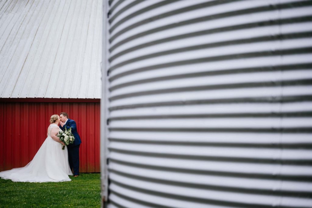 couple kissing in front of red barn Once Upon a Farm wedding