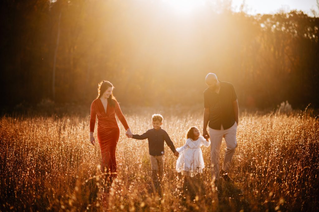 The Higgins family strolling through a golden, sunny field during their portrait session in Charleston, WV.
