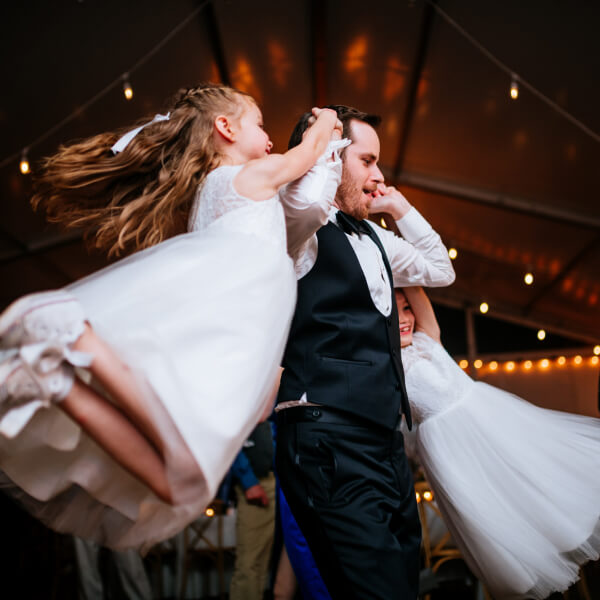 Two children are swung around at a wedding reception.