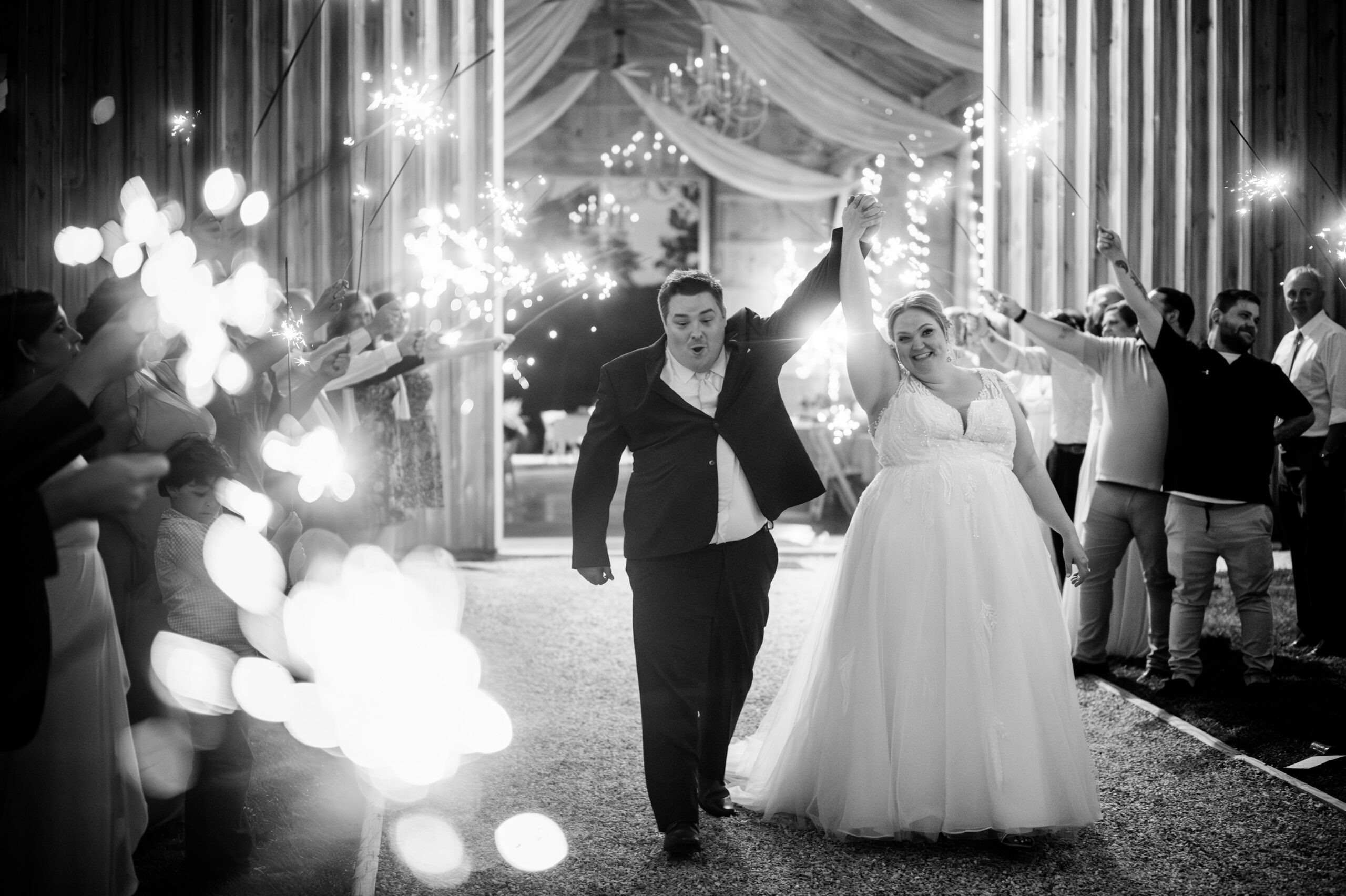 A bride and groom making a happy exit, surrounded by guests holding sparkling lights.