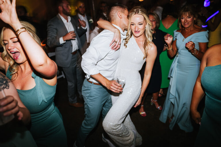 Groom kisses the bride on a packed dance floor.