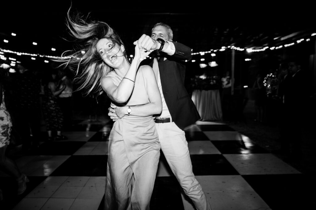 A wedding guest's hair whips through the air as her partner gives her a spin on the dance floor.