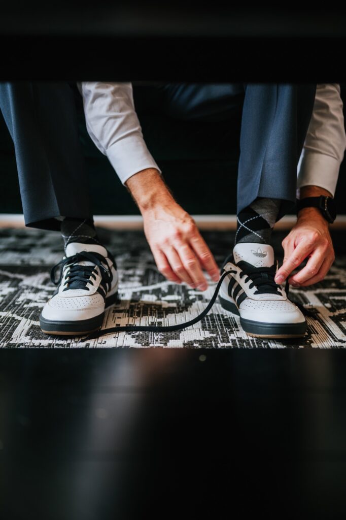 groom tying adidas wedding shoes