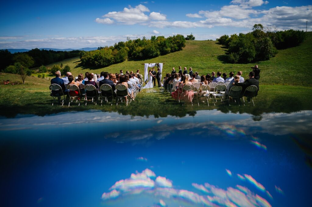 caitlyn and jason exchanging vows with a reflected blue sky at batten green wedding venue