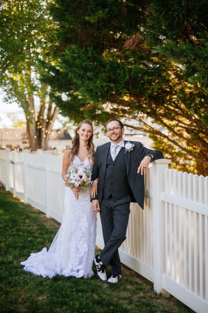 caitlyn and jason smiling beside a fence at batten green wedding venue