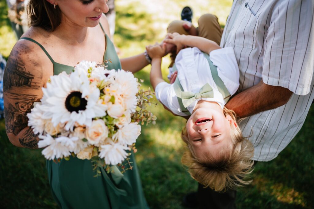 a little boy laughs while being held upside down