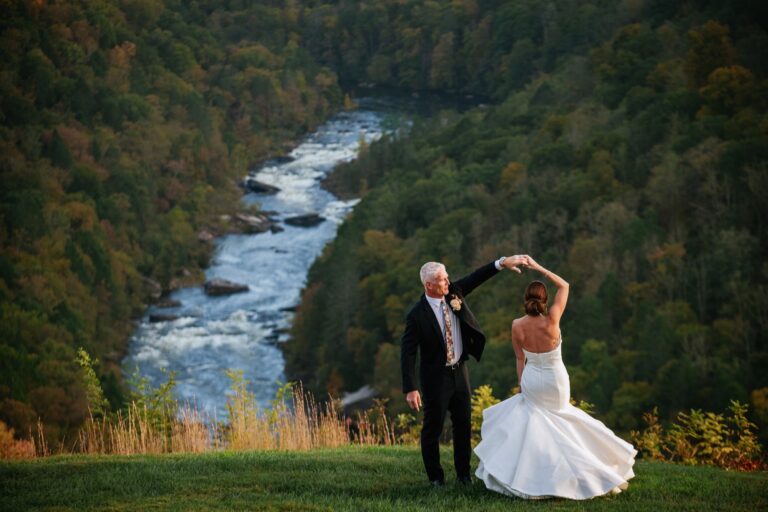 Groom spins bride in front of Gauley River overlook at Wilderness Lodge Summersville WV wedding.