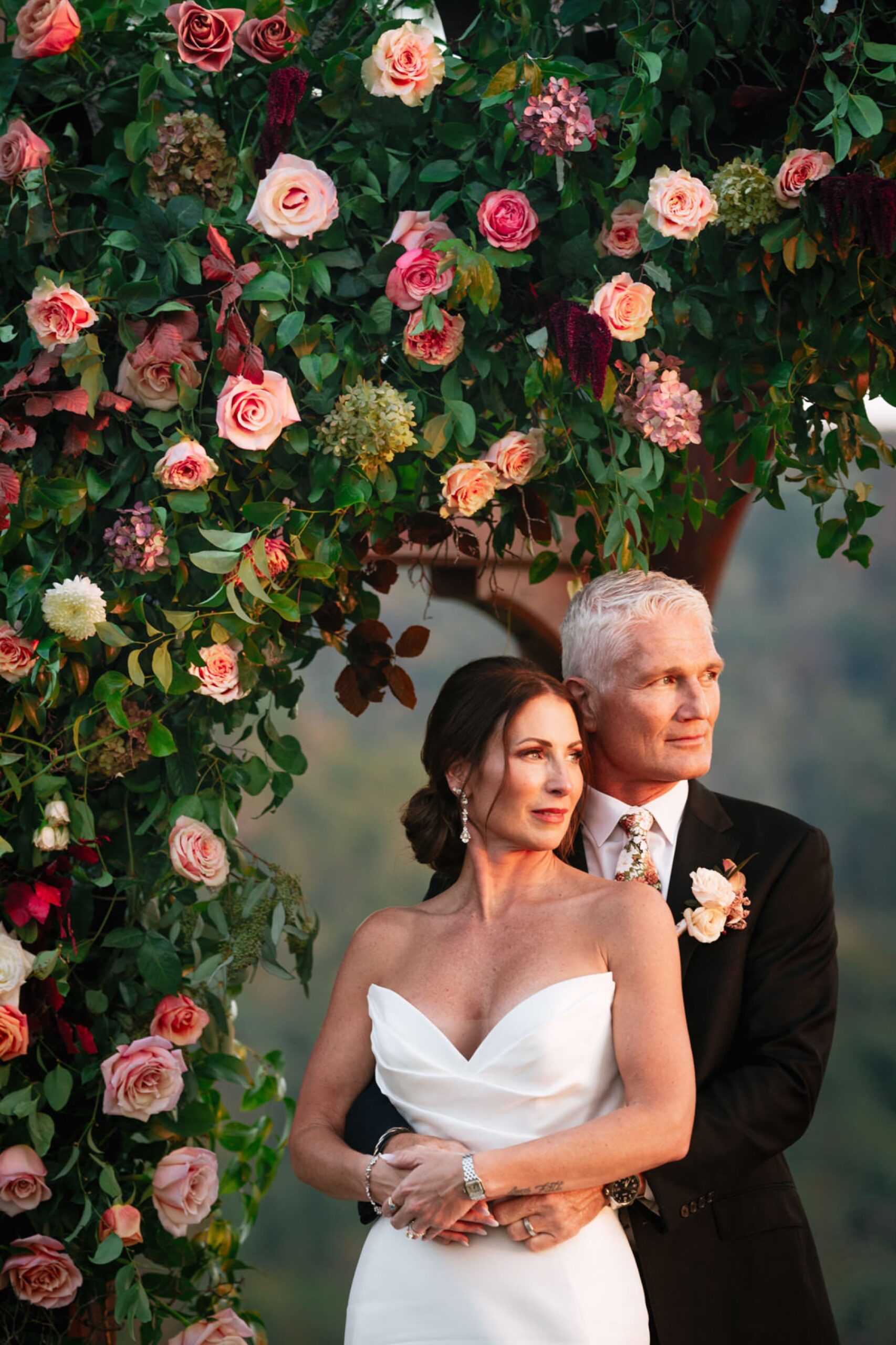 Bride and groom hugging in front of a flower archway at their Wilderness Lodge Summersville WV wedding.