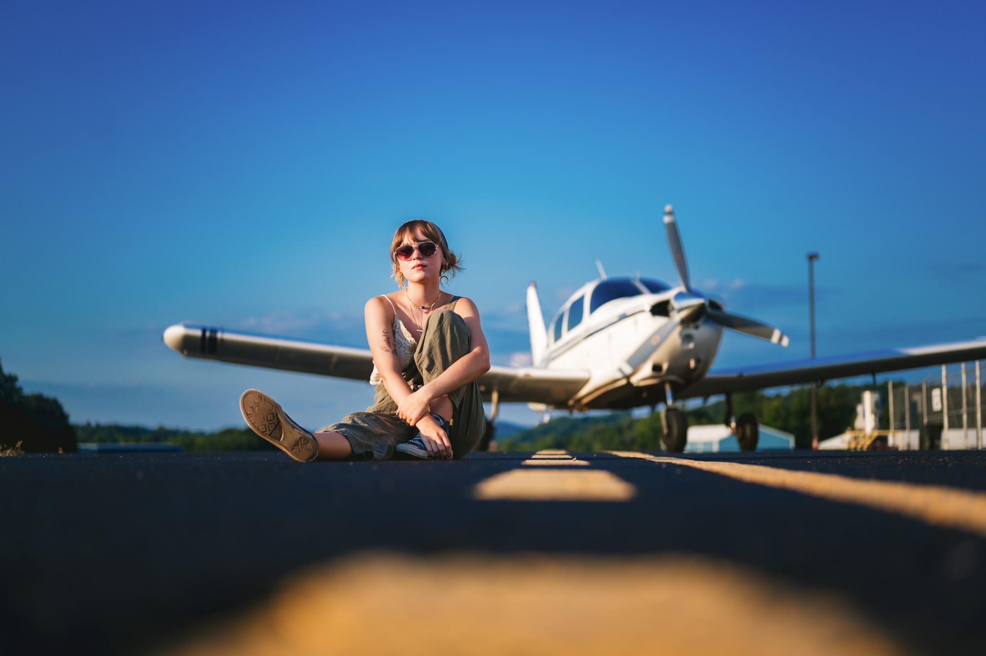 girl sitting on tarmac in front of plane wv high school senior portrtait
