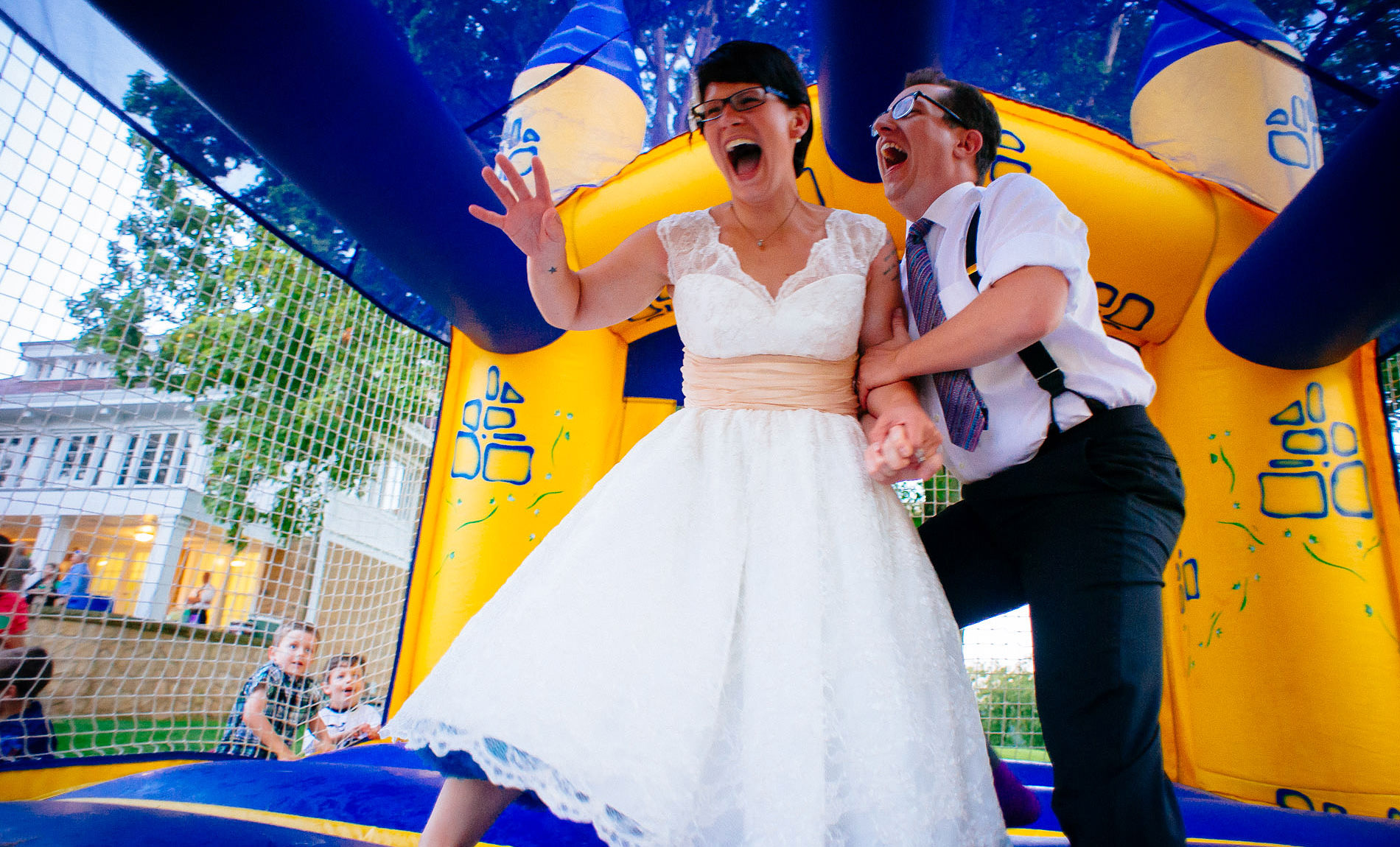 bride and groom jumping in bouncy castle 
