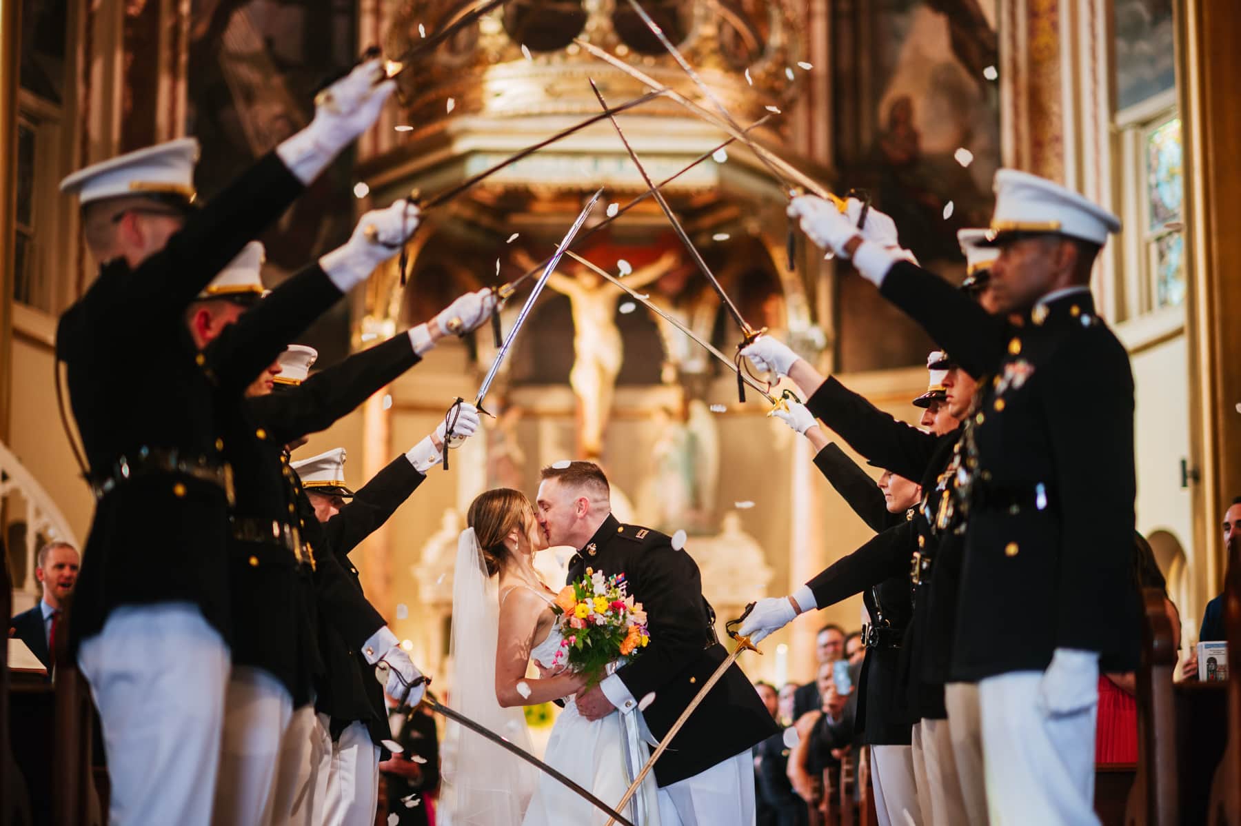 bride and groom kiss with marines raising sabers 