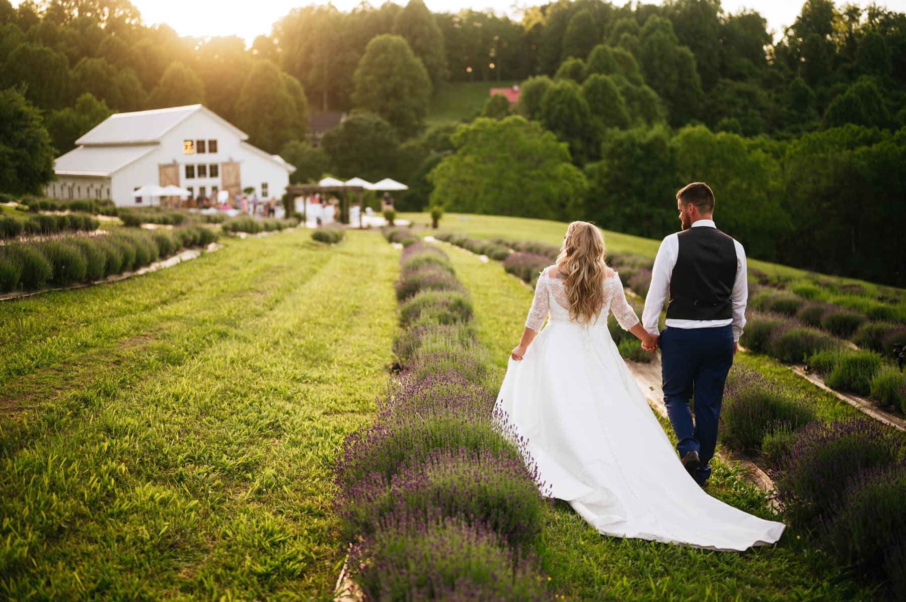 bride and groom walking towards barnstone house lavender wedding 