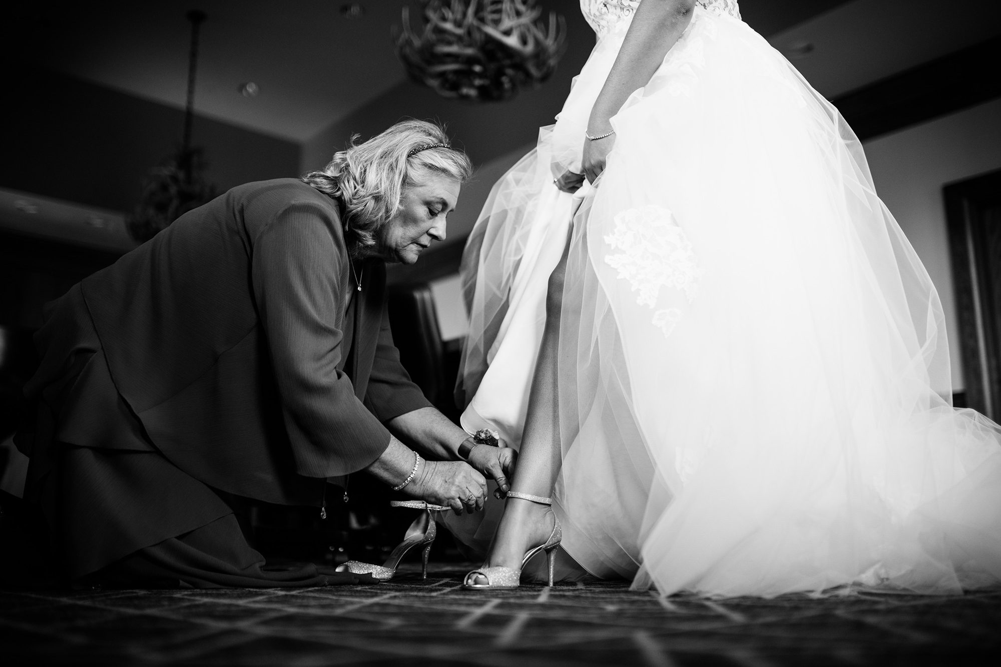 mom putting on brides shoes